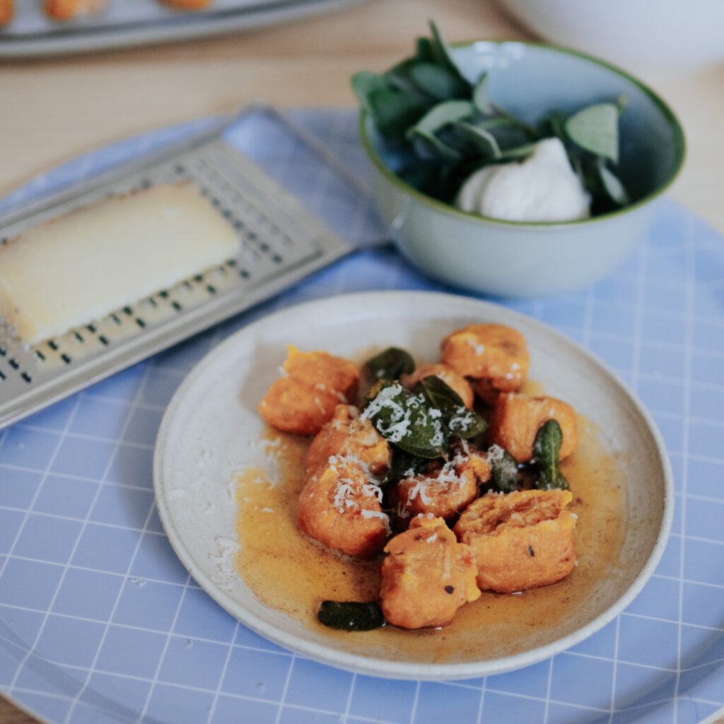 Kürbis Gnocchi mit Salbeibutter und Pecorino auf weißem Teller und hellblauem Tablett von nuukk.