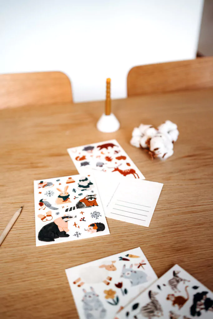Winter Postkarte mit Waldtieren: Waschbär, Dachs, Hase mit Handschuhen und Schal, Eisstern